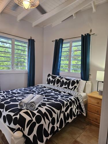 a black and white bed in a room with windows at 216A Upper Level, Deluxe 1 Bedroom in Jolly Harbour
