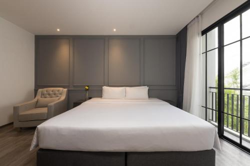 a bedroom with a large white bed and a chair at One Patio Hotel Pattaya - SHA Extra Plus in Pattaya