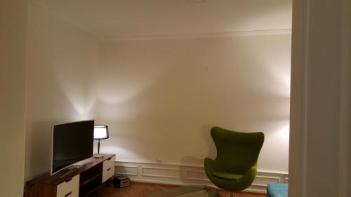 a living room with a green chair and a television at Basel Charme Apartments in Basel