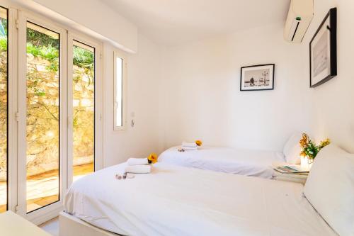 deux lits dans une chambre blanche avec une fenêtre dans l'établissement HENRIETTA AP4070 - avenue Soleil d'Or - Villefranche-sur-Mer, à Villefranche-sur-Mer