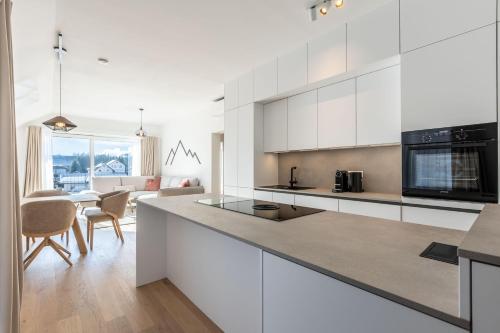 a kitchen with white cabinets and a living room at Alpine Suite Spot in Bad Mitterndorf