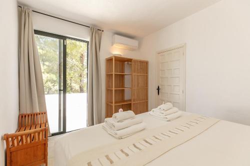 a white bedroom with a bed with towels on it at Sunset villa with pool and seaview in Cala Tarida