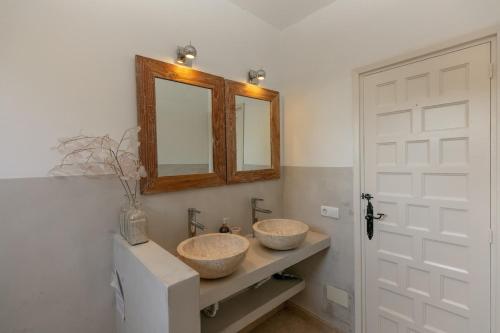 two sinks in a bathroom with a mirror and a door at Sunset villa with pool and seaview in Cala Tarida