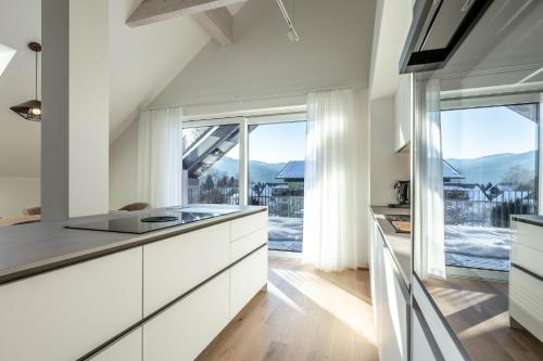 a kitchen with white cabinets and a large window at Alpine Suite Spot in Bad Mitterndorf