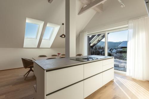a kitchen with white cabinets and a large window at Alpine Suite Spot in Bad Mitterndorf