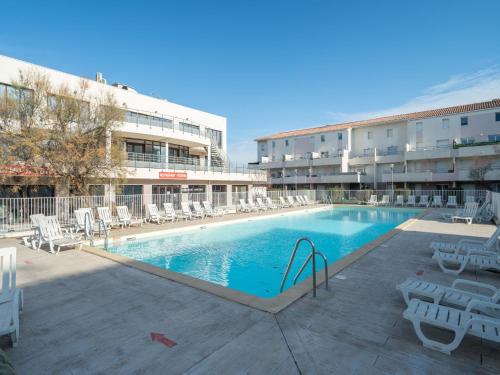 une grande piscine avec des chaises et un bâtiment dans l'établissement Cap Camargue B N 26 - 2P4, au Grau-du-Roi
