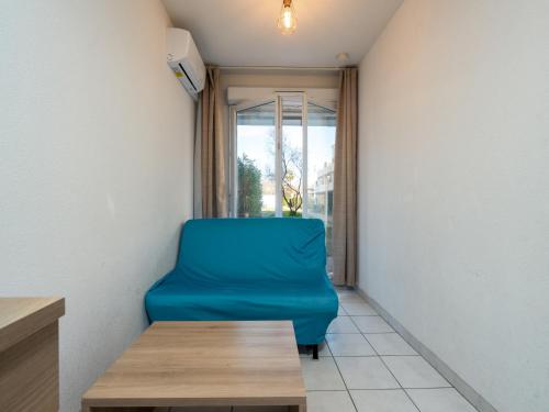 une chaise bleue dans une chambre avec fenêtre dans l'établissement Cap Camargue B N 26 - 2P4, au Grau-du-Roi