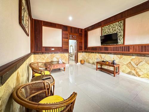 a living room with chairs and a tv on a wall at Puri Karang Residence in Bangli