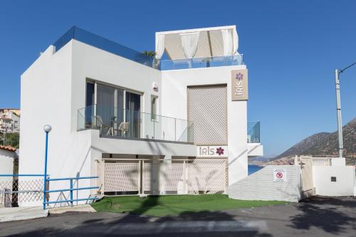 a white house with a balcony on top of it at Villa Iris, beachfront, with jacuzzi, up to 9 guests, Mpali beach, Rethymno! in Balíon