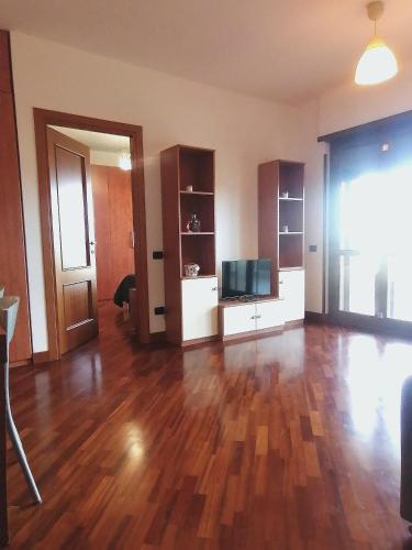 an empty living room with a wooden floor and a television at hopefco in Fiumicino