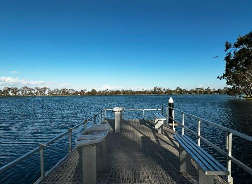 a dock with two benches on the water at Woomelang Cabin Silo Trail Two Bedroom Cabin Queen and KSing in Woomelang