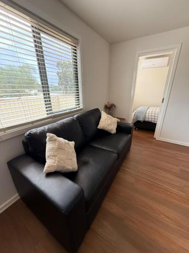 a black leather couch in a living room with two pillows at Woomelang Cabin Silo Trail Two Bedroom Cabin Queen and KSing in Woomelang