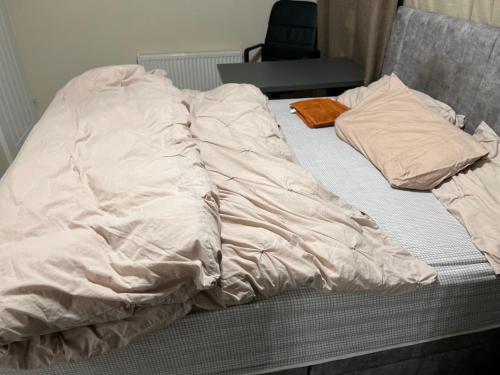 an unmade bed with sheets and pillows on it at En suite Bedroom in Milton Keynes in Bletchley
