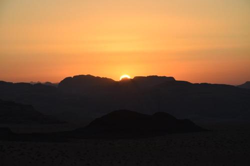 a sunset over the mountains in the desert at Wadi Rum Nights in Wadi Rum