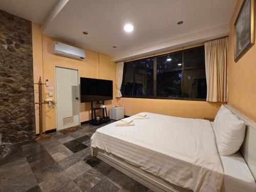 a bedroom with a large white bed and a television at Puprai Tarnnarm Resort in Thong Pha Phum