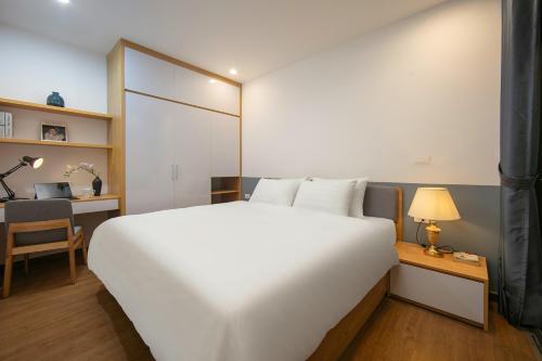 a bedroom with a large white bed and a desk at Westlake Pearl Apartment - Hotel & Pearl Spa in Hanoi