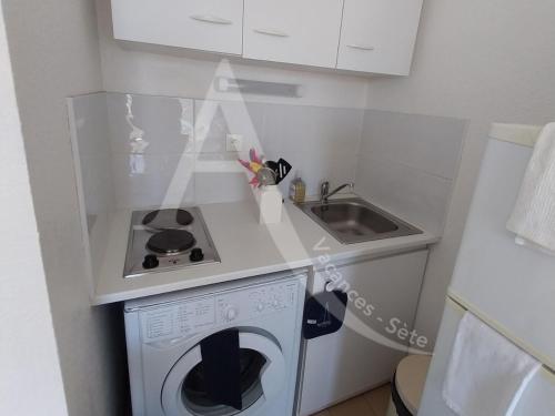 une petite cuisine avec une machine à laver et un évier dans l'établissement Coquet T2 avec balcon en plein coeur du quartier de la Corniche proche commerces et plages, à Sète