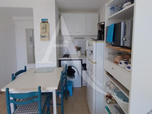 une cuisine avec un comptoir blanc et une table avec des chaises dans l'établissement Coquet T2 avec balcon en plein coeur du quartier de la Corniche proche commerces et plages, à Sète