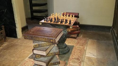 a chess board sitting on top of books at Entire Castle & Grounds for 18, Banquet Hall & BBQ in Trowbridge