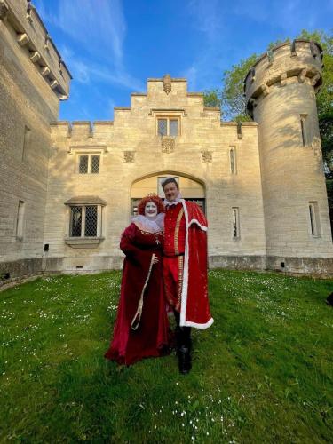 a man and woman dressed in costumes standing in front of a castle at Entire Castle & Grounds for 18, Banquet Hall & BBQ in Trowbridge