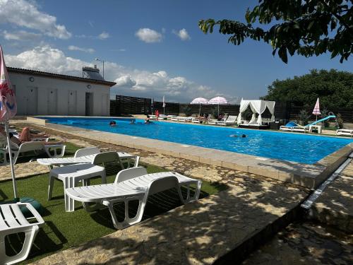 a swimming pool with white tables and chairs next to it at Pensiunea Maria Agighiol in Agighiol