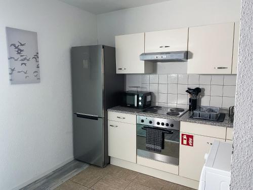 eine Küche mit weißen Schränken und einem Edelstahlkühlschrank in der Unterkunft bookandstay24 Dietzenbach 2 Zimmerwohnung mit Balkon, Küche und Parkplatz-14 in Dietzenbach
