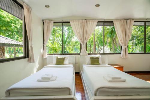 two beds in a room with large windows at Puprai Tarnnarm Resort in Thong Pha Phum