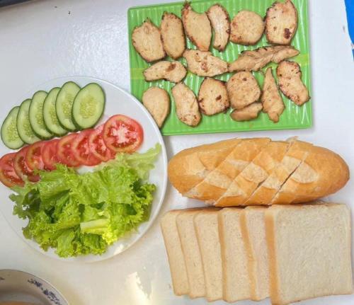 a table with a plate of food and a sandwich at HOMESTAY Hoàng GIa in Ấp Ông Tú