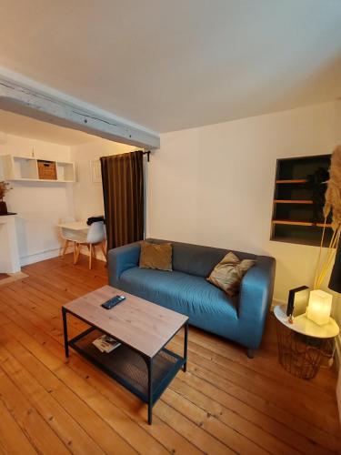 un salon avec un canapé bleu et une table dans l'établissement Charmant studio rénové, à Caen