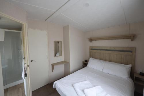 a bedroom with a bed with white sheets and a mirror at Mercury Yacht Harbour and Holiday Park in Bursledon
