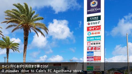 a palm tree in front of a building with signs at 海の見える高層階グループファミリー歓迎コストコ近くThe琉球タワー9A in Yonabaru