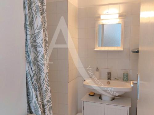 une salle de bain avec un lavabo et un miroir dans l'établissement T3 en plein coeur Corniche et proche des plages, à Sète