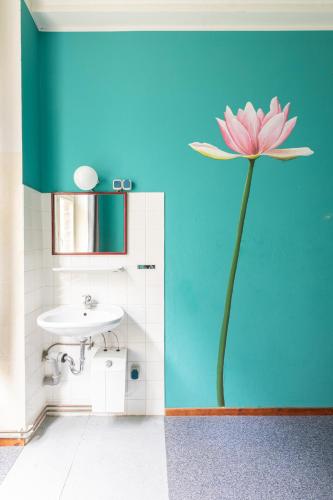 a bathroom with a pink flower painted on the wall at Die Fabrik - Hostel in Berlin