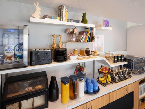 a kitchen with white shelves and a counter with food at ibis Budget Wentworthville in Wentworthville