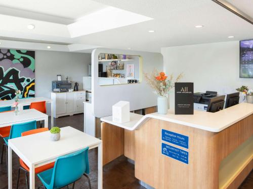two views of a salon with tables and chairs at ibis Budget Wentworthville in Wentworthville