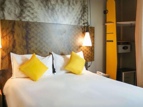 a bedroom with a white bed with two yellow pillows at Ibis Sfax in Sfax