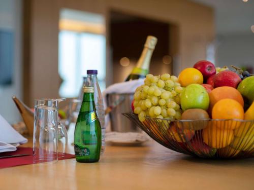 a table with a bowl of fruit and two bottles of wine at Novotel Jazan in Jazan