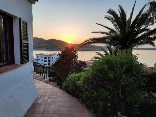 a sunset from a building with a palm tree at El ALCOR 2 Apartment with wonderful sea views in Fornells