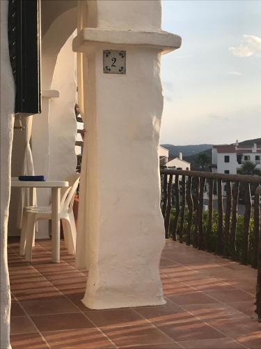 a white building with a clock on a balcony at El ALCOR 2 Apartment with wonderful sea views in Fornells