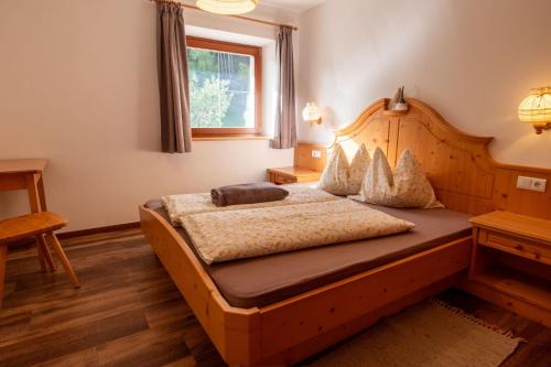 sypialnia z drewnianym łóżkiem i oknem w obiekcie Planitzhof w mieście Castelrotto