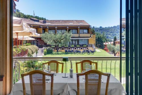 a table with chairs and a view of a house at Poiano Garda Resort Hotel in Garda