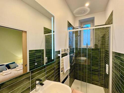La salle de bains est pourvue d'un lavabo et d'une douche avec du carrelage vert. dans l'établissement La suite Jade de Reims - Cathédrale, à Reims