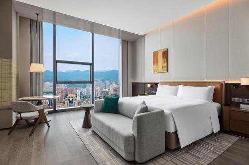 a bedroom with a bed and a chair and a large window at Conrad Chongqing - Indulge in the magical 8D city landscape in Chongqing