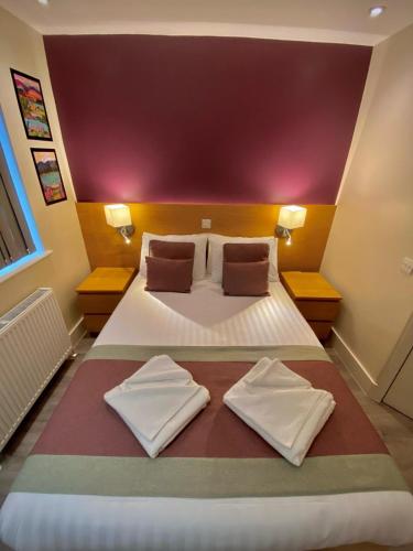 a bedroom with a large bed with two towels on it at Holtwhites Hotel in Enfield