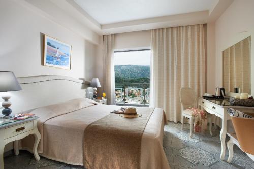 a hotel room with a bed and a desk and a window at Panorama Botsaris Apartments in Syvota
