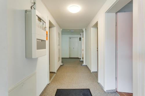 a hallway with white walls and a hallway with a rug at Anstatthotel Luzern - app self-check-in in Luzern