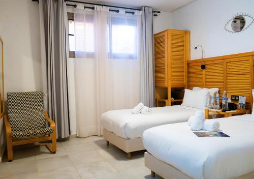 a hotel room with two beds and a chair at Hotel Dakhla Club & SPA in Dakhla