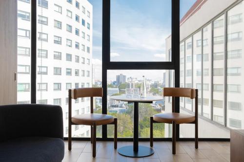 a table and two chairs in a room with a window at Crisol Suites Condesa in Mexico City