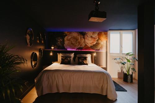 une chambre avec un lit avec un tableau sur le mur dans l'établissement L'alcôve Clisson-Love room- Gîte Romantique-SPA, à Clisson