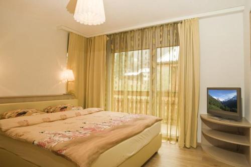 - une chambre avec un lit, une télévision et une fenêtre dans l'établissement Residenz Ambassador A33, à Loèche-les-Bains